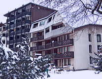 a house covered in snow in front of a building